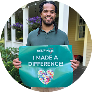 Woman holding a banner that reads "DCU For Kids: I Made A Difference"
