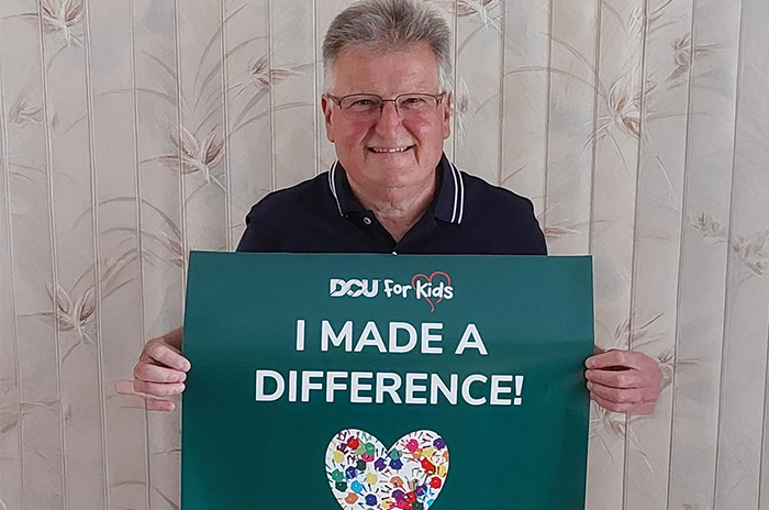 DFK Cash Raffle winner holding a sign that reads "I Made a Difference!"