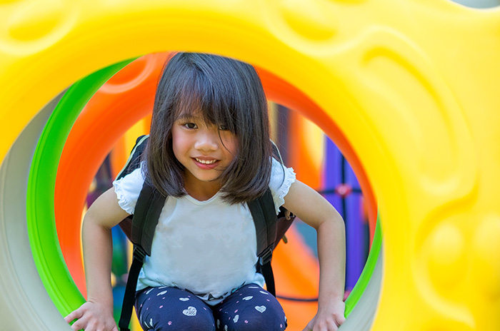 Girl smiling inside a playground tunnel